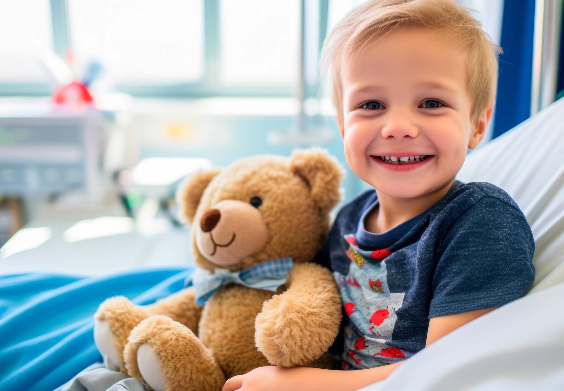 A smiling child with a teddy bear in a hospital bed